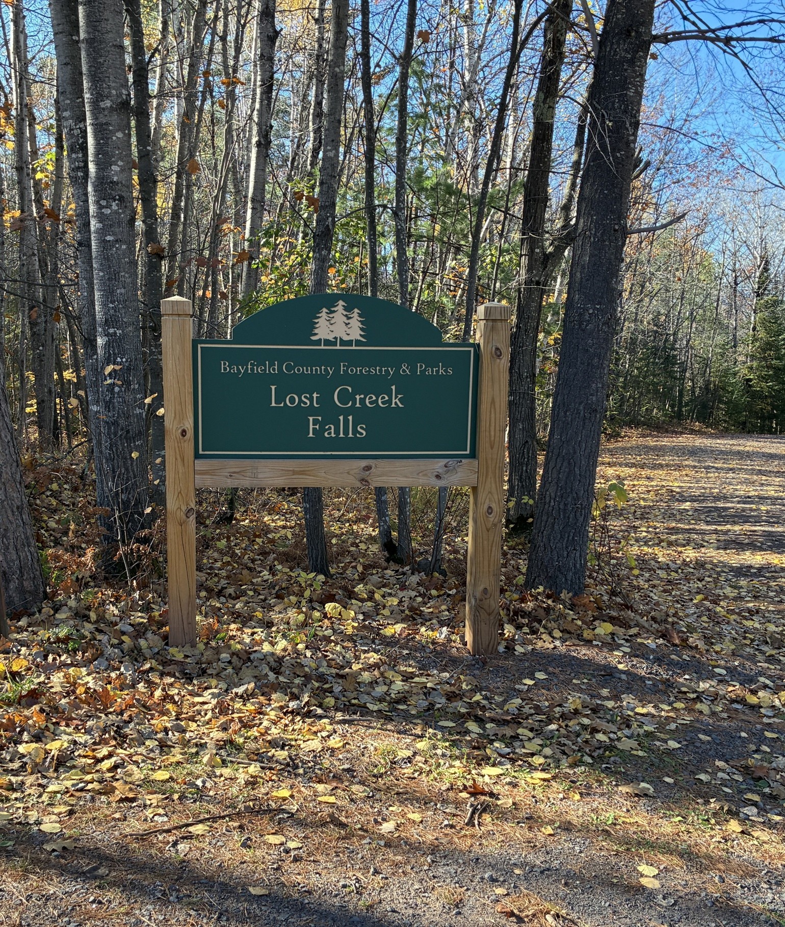 Entrance sign for Lost Creek Falls, a Bayfield County Forestry and Parks property, surrounded by autumn forest foliage