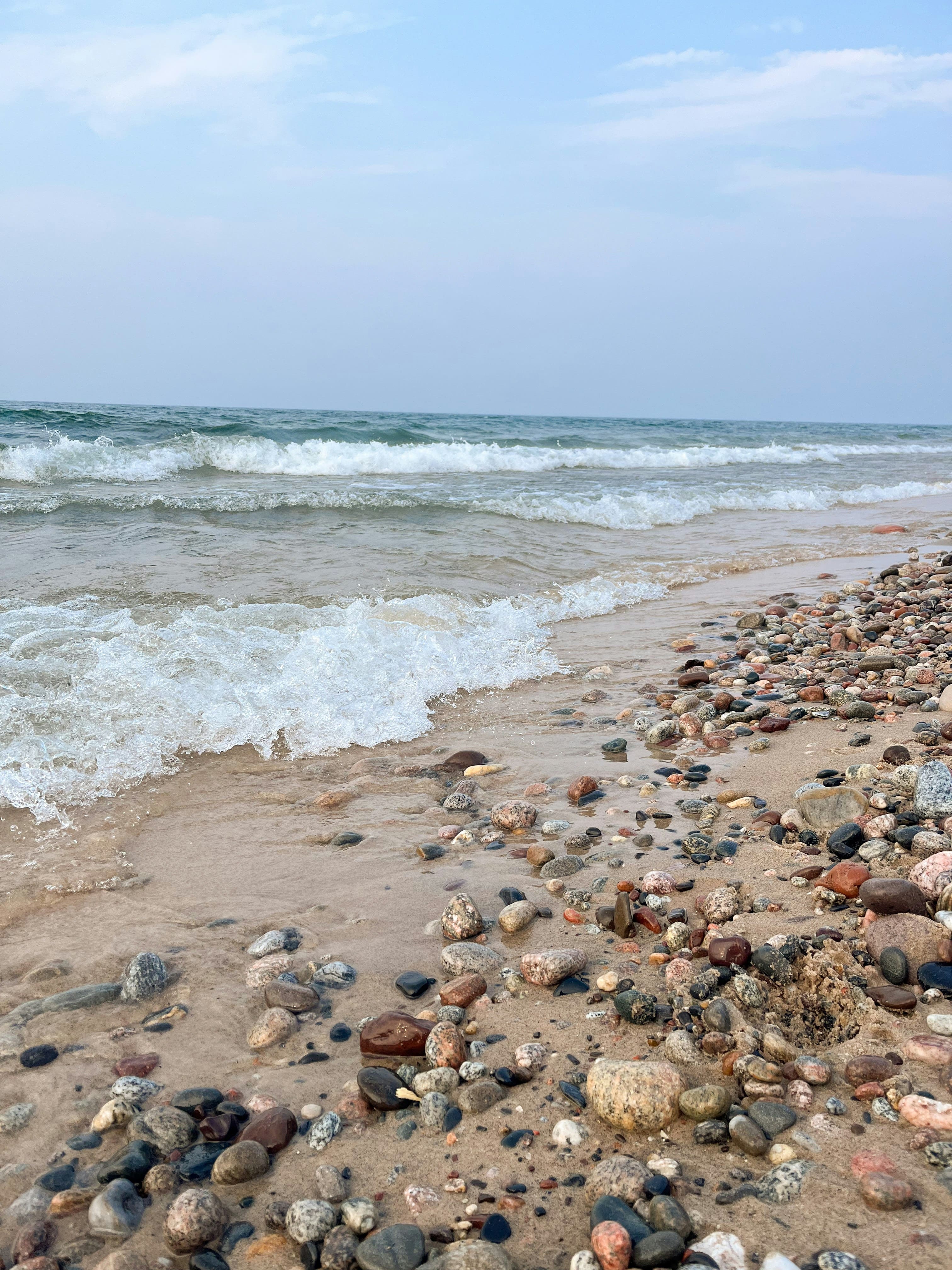 Waves washing over a rocky Lake Superior shoreline with colorful stones in the foreground