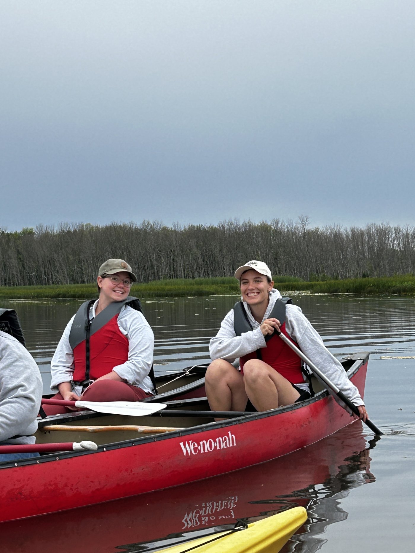 Two participants smiling from a canoe during the natural history paddle through the Fish Creek sloughs