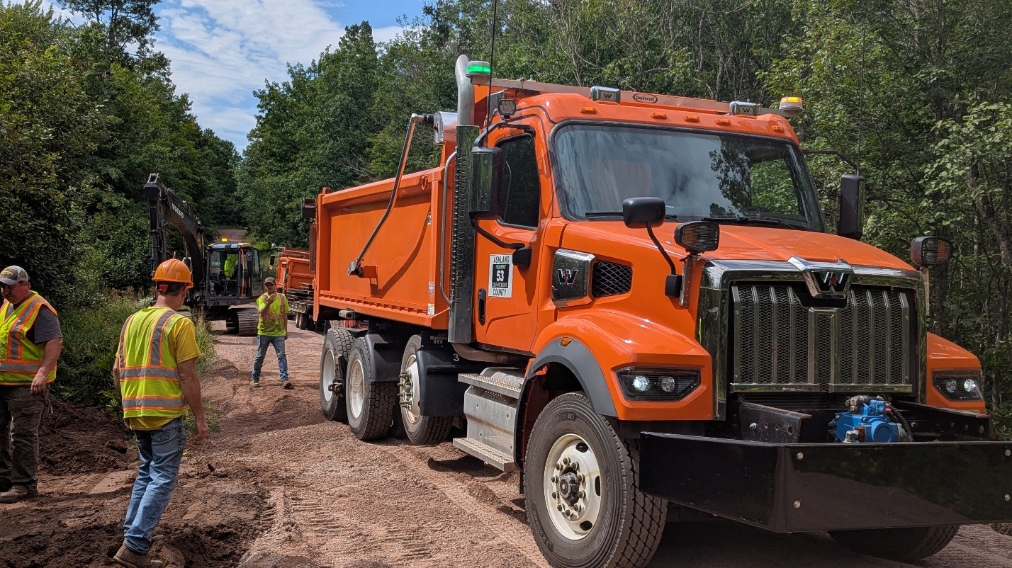 Multiple excavators working on culvert replacement along county road