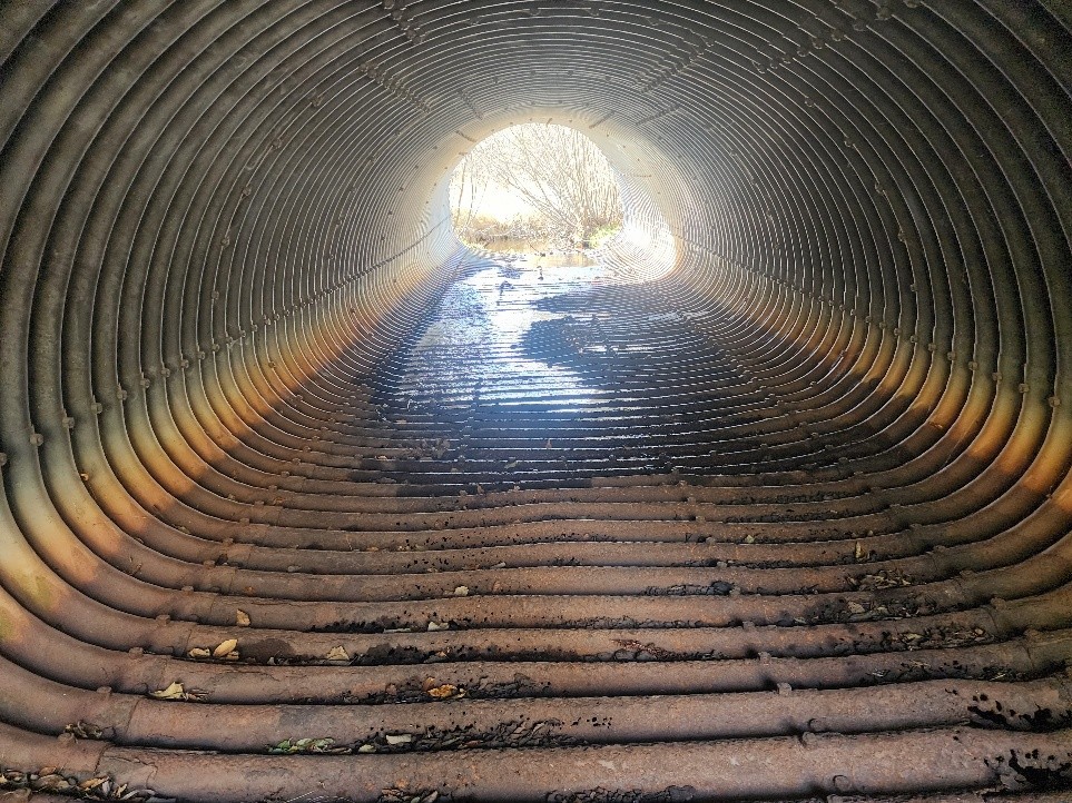Corroded culvert floor with holes from constant stream abrasion at Happy Creek