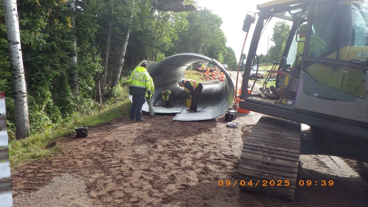 Construction worker standing next to new culvert being placed at Happy Creek