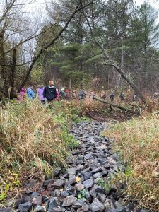 Symposium participants walking along a rock-lined stream restoration feature during the 2024 LSC field tour of Act 157 project sites