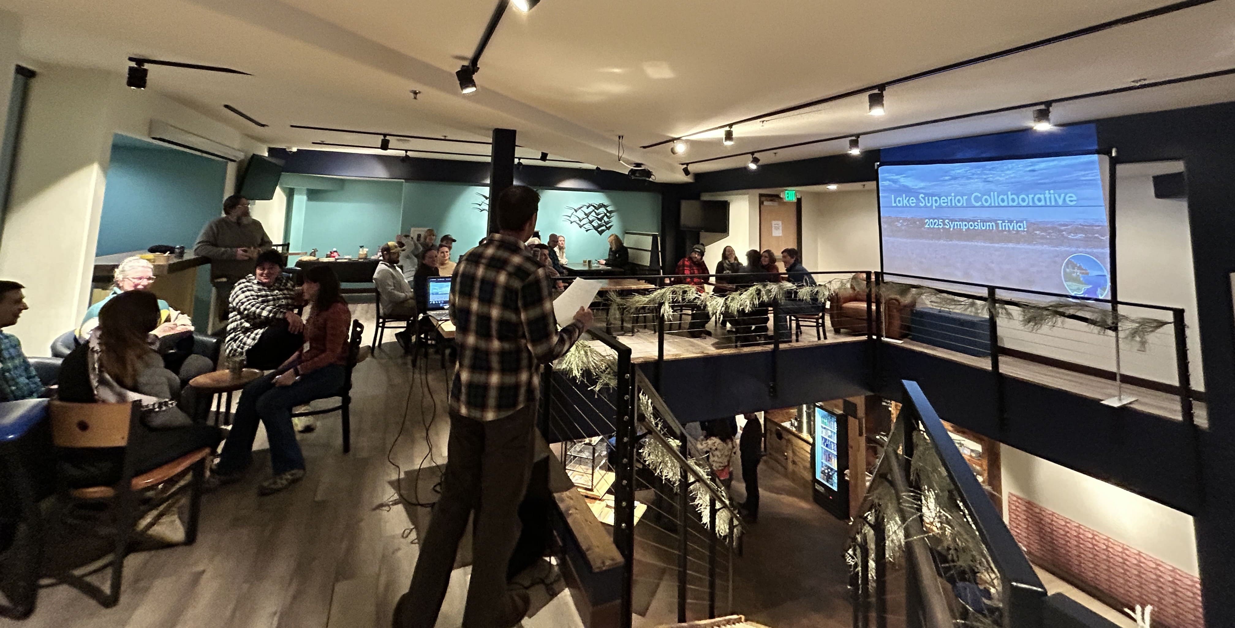 LSC Symposium attendees gathered for the evening social and trivia event, with a Lake Superior Collaborative branded screen visible in the background